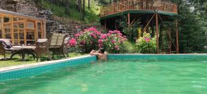 a man in the water in a swimming pool at Kudrat - A Boutique Homestay- Tirthan Valley in Banjār