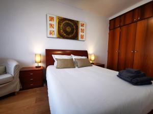 a bedroom with a large white bed and a couch at Gustavo's Place in Sines