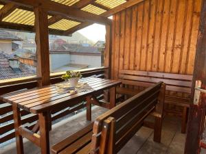 eine Veranda mit einem Holztisch, einer Bank und einem Fenster in der Unterkunft Ambra Dream Home in Câmpulung Moldovenesc