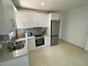 a kitchen with white cabinets and a stainless steel refrigerator at Loft Apartments in Sarandë