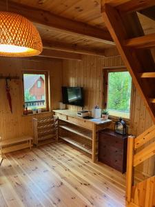 een woonkamer met een televisie in een houten huisje bij Domek całoroczny HAWAJE nad jeziorem Kazub in Cieciorka