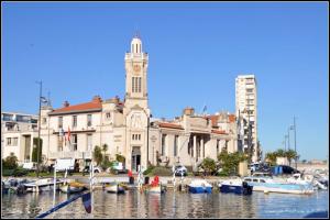 un bâtiment avec une tour d'horloge et des bateaux dans un port dans l'établissement Appartement avec terrasse 10M2 centre ville 300 m Sète, à Sète