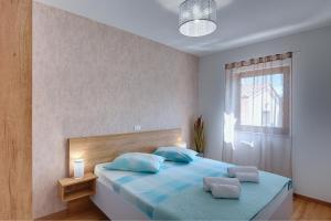 a bedroom with a bed with blue pillows and a window at Apartments Buic in Vinkuran