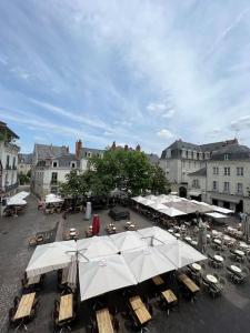 an outdoor patio with tables and white umbrellas at T2 vue sur La Place Plumereau in Tours