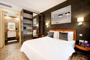 um quarto com uma grande cama branca e uma casa de banho em Battistini Boutique Living Hotel and Spa, Victoria, Gozo em Victoria