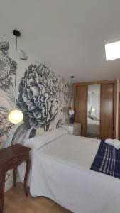 a bedroom with a large white bed with a floral wallpaper at Suite Playa in Miño +28 photos