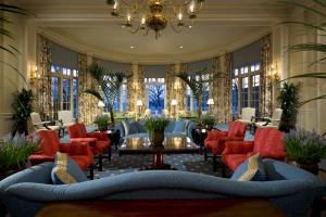 a lobby with red chairs and a table and a chandelier at The Otesaga Resort Hotel in Cooperstown