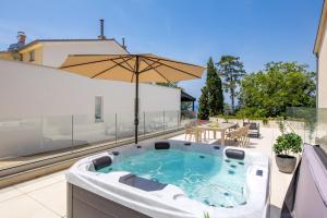 a hot tub on a patio with an umbrella at VILLA MAR - LUXURY APARTMENTS with pool and hot tub in Selce, 20 meters from the beach, Boat tours option in Selce