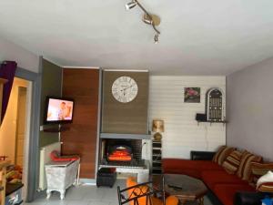 a living room with a red couch and a clock at Loue maison quartier calme in Royan