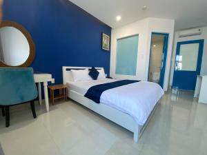 a blue bedroom with a large bed and a desk at Alicia Hotel in Tuy Hoa