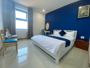 a bedroom with a large bed with a blue wall at Alicia Hotel in Tuy Hoa