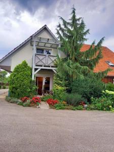 une maison avec un arbre et des fleurs devant elle dans l'établissement Gemütliche Familienwohnung, à Lannach