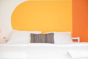 1 cama con almohadas blancas y pared de color naranja en The White Hill Guesthouse, en Yeruham