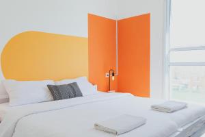 1 dormitorio con cama blanca y cabecero naranja en The White Hill Guesthouse, en Yeruham