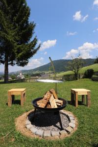 a fire pit in a field with two benches at Hus8 Krumbach in Krumbach