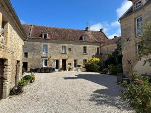 einen Innenhof eines alten Steingebäudes mit Stühlen in der Unterkunft Chambres d’hôtes de l’Ancienne Auberge in Thaon