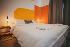 a bedroom with a large white bed with an orange headboard at The White Hill Guesthouse in Yeroẖam