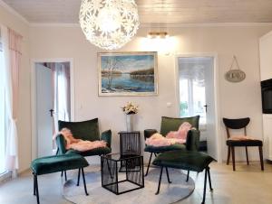 a living room with green chairs and a chandelier at Luxury Apartment Slavica in Vodice