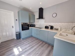 una cocina con armarios azules y un reloj en la pared en The Forge by Cliftonvalley Apartments, en Bristol