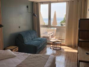 a bedroom with a couch and a chair in front of a window at Les Alcyons in Le Lavandou