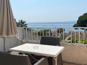 a white table and chairs on a balcony with the ocean at Les Alcyons in Le Lavandou