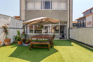 un patio con tavolo e ombrellone su un balcone di Travel & Live Aliados Apartment a Porto