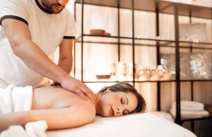 Um homem está a dar uma massagem a uma mulher numa cama. em Hotel Litovel em Luhačovice