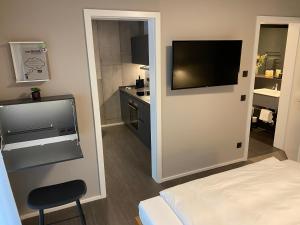 ein Hotelzimmer mit einem TV an der Wand und einem Bett in der Unterkunft Timehouse Serviced Apartments in München