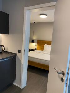 Schlafzimmer mit einem Bett und einer Tür, die in ein Zimmer führt in der Unterkunft Timehouse Serviced Apartments in München