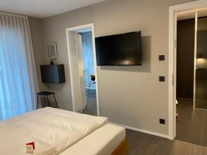 Schlafzimmer mit einem Bett und einem Flachbild-TV an der Wand in der Unterkunft Timehouse Serviced Apartments in München