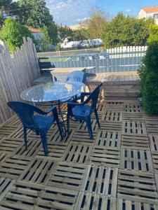 a patio with a glass table and chairs on a deck at Loue maison quartier calme in Royan