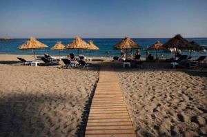 a sandy beach with umbrellas and people on the beach at achlia beach apartments 1 in Ierapetra