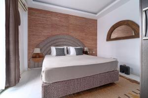 a bedroom with a large bed and a brick wall at Arco Beach Hotel in Agia Paraskevi