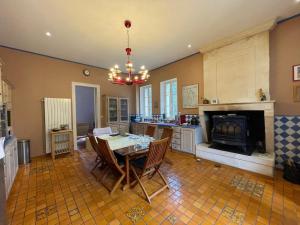 a kitchen with a dining table and a fireplace at Le Jardin Umal in Montendre