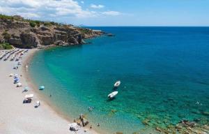 a beach with people and a boat in the water at achlia beach apartments 1 in Ierapetra