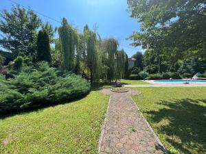 a path in a garden with trees and a pool at Villa Donata in Sarajevo
