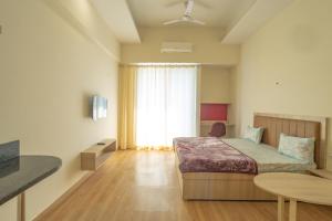 1 dormitorio con cama, mesa y ventana en Top Luxuries Couple Friendly Stay in Gaur Mall by Taj Studios, en Ghaziabad