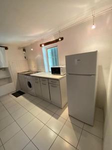 a white kitchen with a refrigerator and a window at Joli studio en plein centre ville - Nyons in Nyons