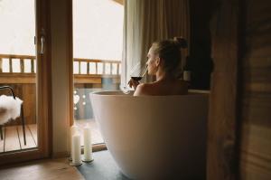 une femme assise dans une baignoire avec un verre de vin dans l'établissement Gletscher-Chalet Stubai, à Neustift im Stubaital