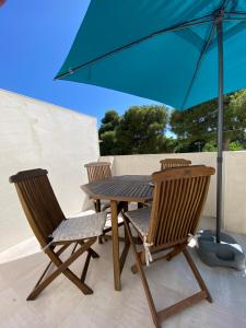 een houten tafel en twee stoelen met een parasol bij Le petit prince in Balaruc-les-Bains