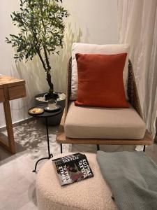 a room with a chair with a red pillow and a magazine at O live Kalamata in Kalamata +10 photos