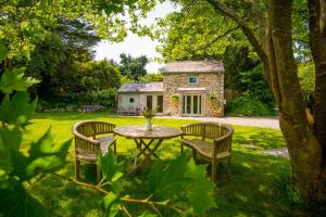 a table and chairs in front of a stone house at Pinetum Garden Cottages in St Austell
