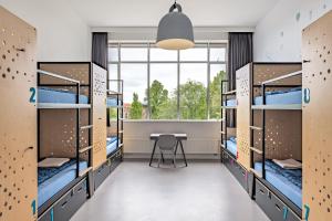 ein Zimmer mit Etagenbetten mit Tisch und Fenster in der Unterkunft Stayokay Hostel Amsterdam Oost in Amsterdam