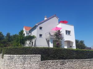a white house with a pink umbrella on top of a wall at Apartmani Scripea in Škrip