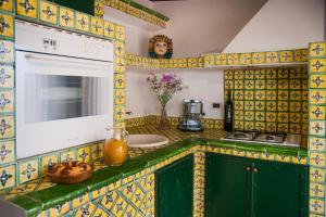 a kitchen with green cabinets and yellow tiles at B&B Casa Andrea in Taormina