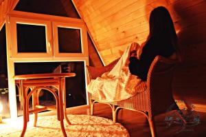 a woman sitting in a chair in a room at Wzgórze w Cieniu Lasu in Łukowica