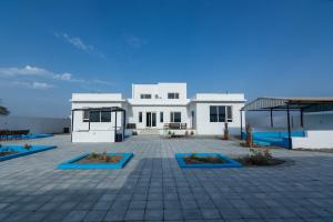 a large white house with a patio in front of it at The One chalet Oman in Bū ‘Abālī
