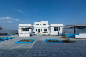 uma grande casa branca com um pátio em frente em The One chalet Oman em Bū ‘Abālī