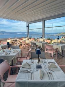 um restaurante com mesas e cadeiras brancas e janelas em Sol Marina Palace Hotel - All Inclusive & Adults Only em Nessebar
