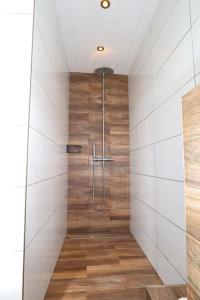 uma casa de banho com um chuveiro com paredes brancas e pisos em madeira em Eastbourne Haven em Eastbourne